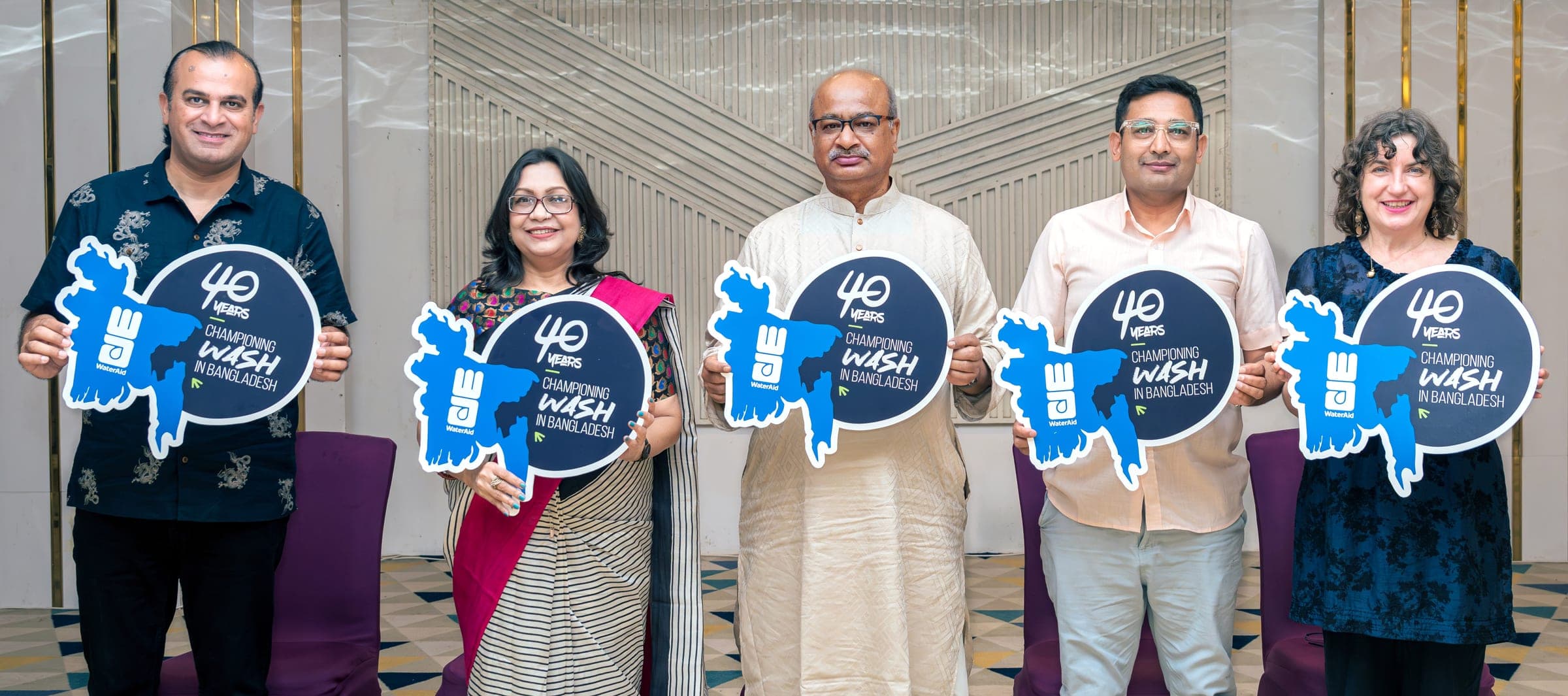 Five colleagues and partners on stage at the 28 June 2026 launch event, each holding a cutout of the WaterAid Bangladesh 40th anniversary mark.
